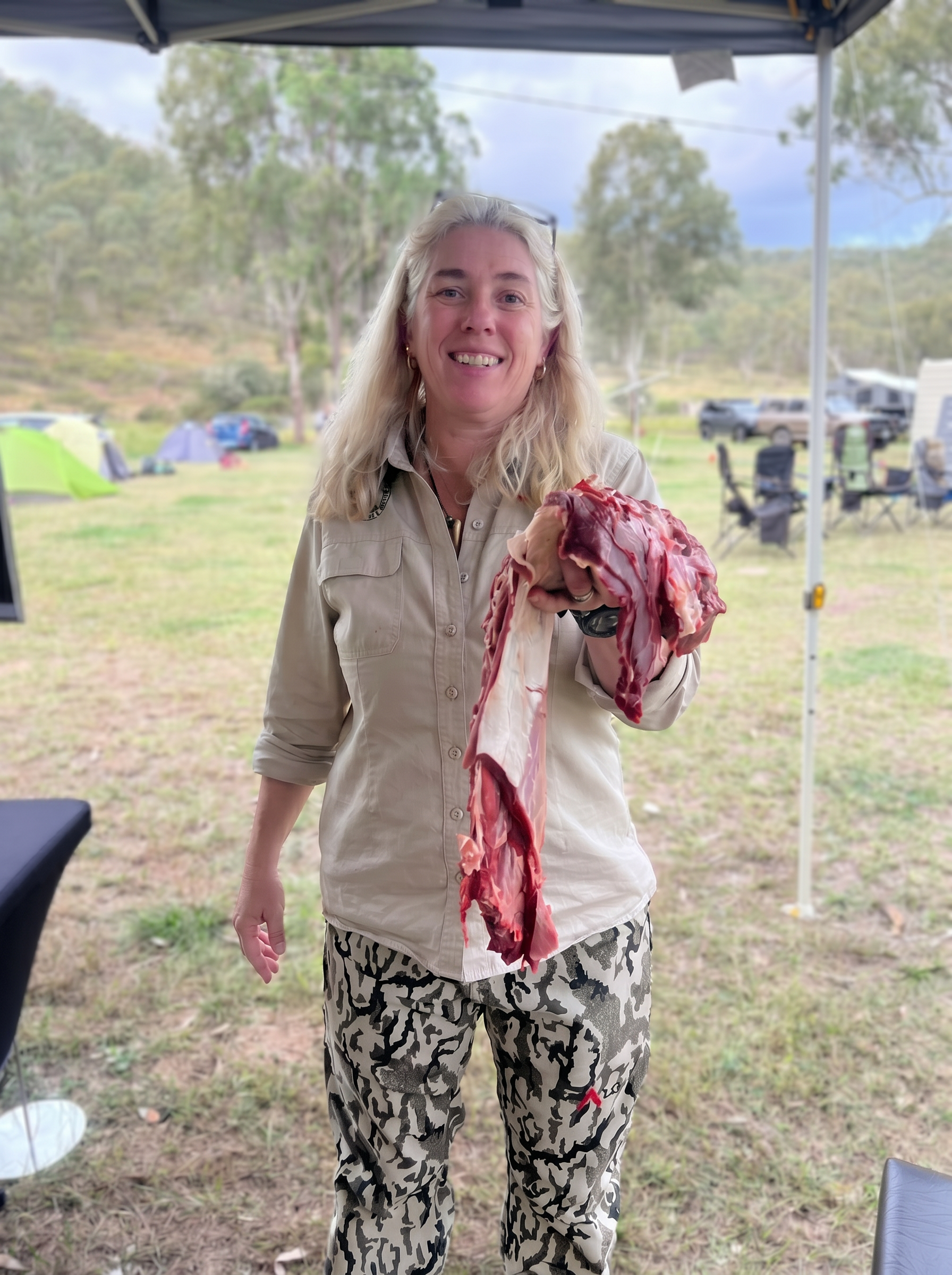 Australian female hunter with a wild-harvested venison shoulder at camp