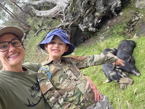 Deanna sitting beside feral pigs she helped track and harvest