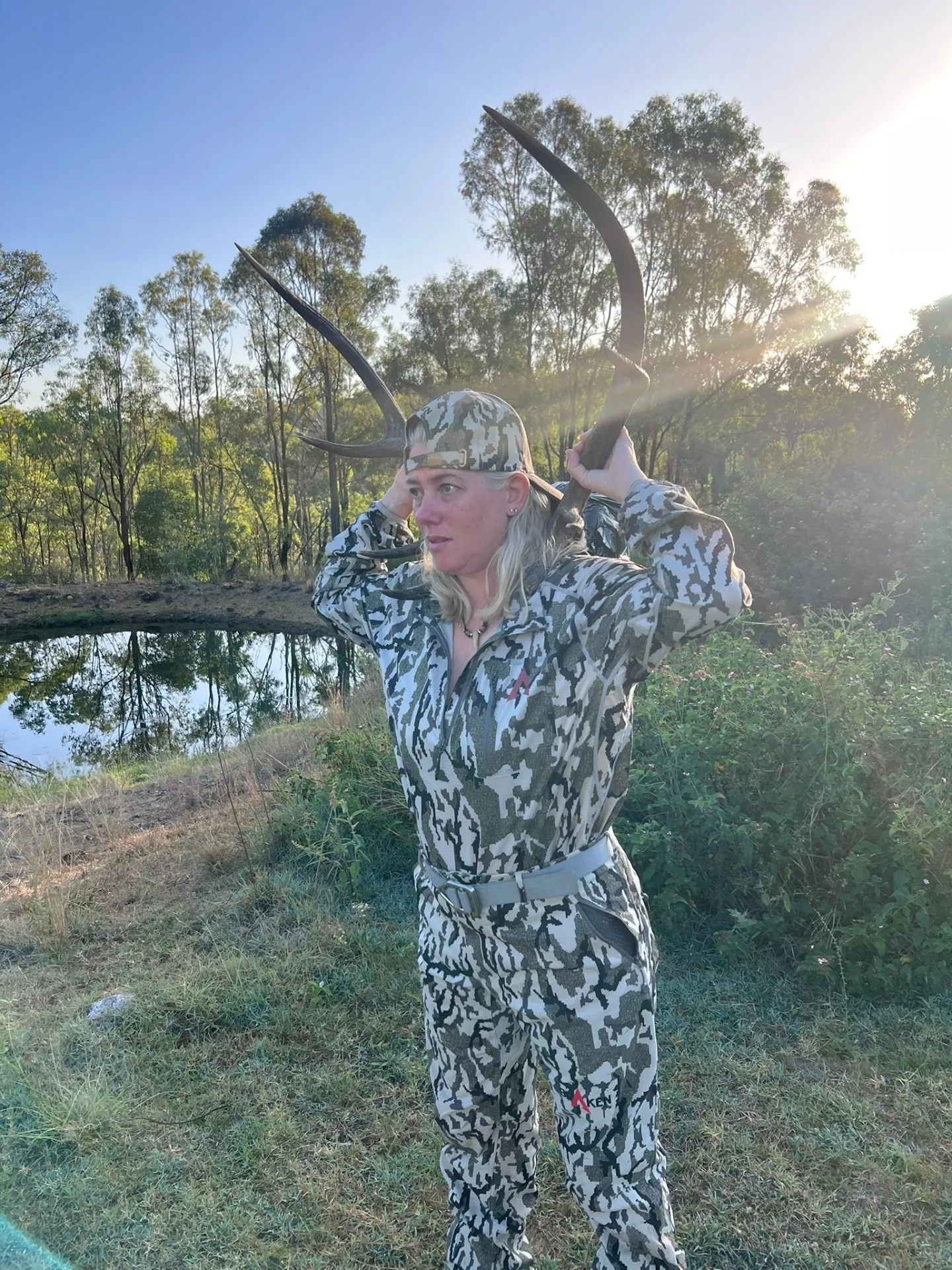 Carly in the Australian bush at sunrise, holding a set of antlers